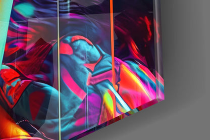 Close-up angled view of multicolored glass wall art panels displaying vibrant neon red, cyan, magenta, and yellow abstract facial features with glossy reflective surface.