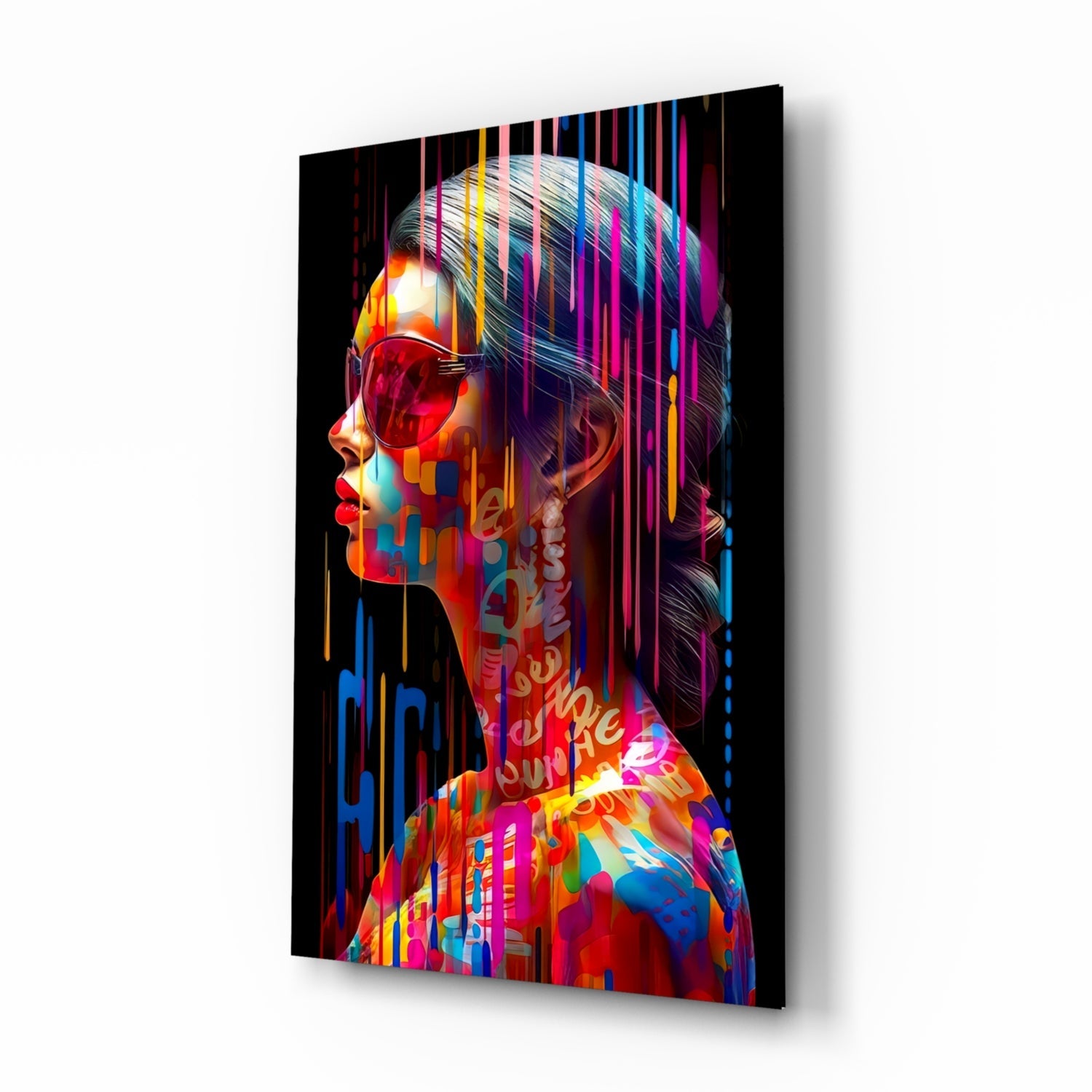Angled view of a glass wall art panel displaying a colorful neon-style portrait with vibrant overlaid text and geometric patterns on black background.