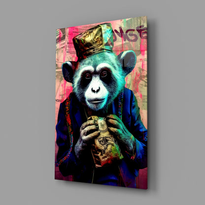 A glass wall art panel displaying a stylized chimpanzee in blue clothing and gold hat holding a coin, set against a colorful pink and turquoise collaged background.