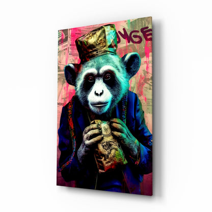 Angled view of glass wall art featuring a stylized chimpanzee in blue jacket and gold crown holding a coin, vibrant pink and teal background with text.