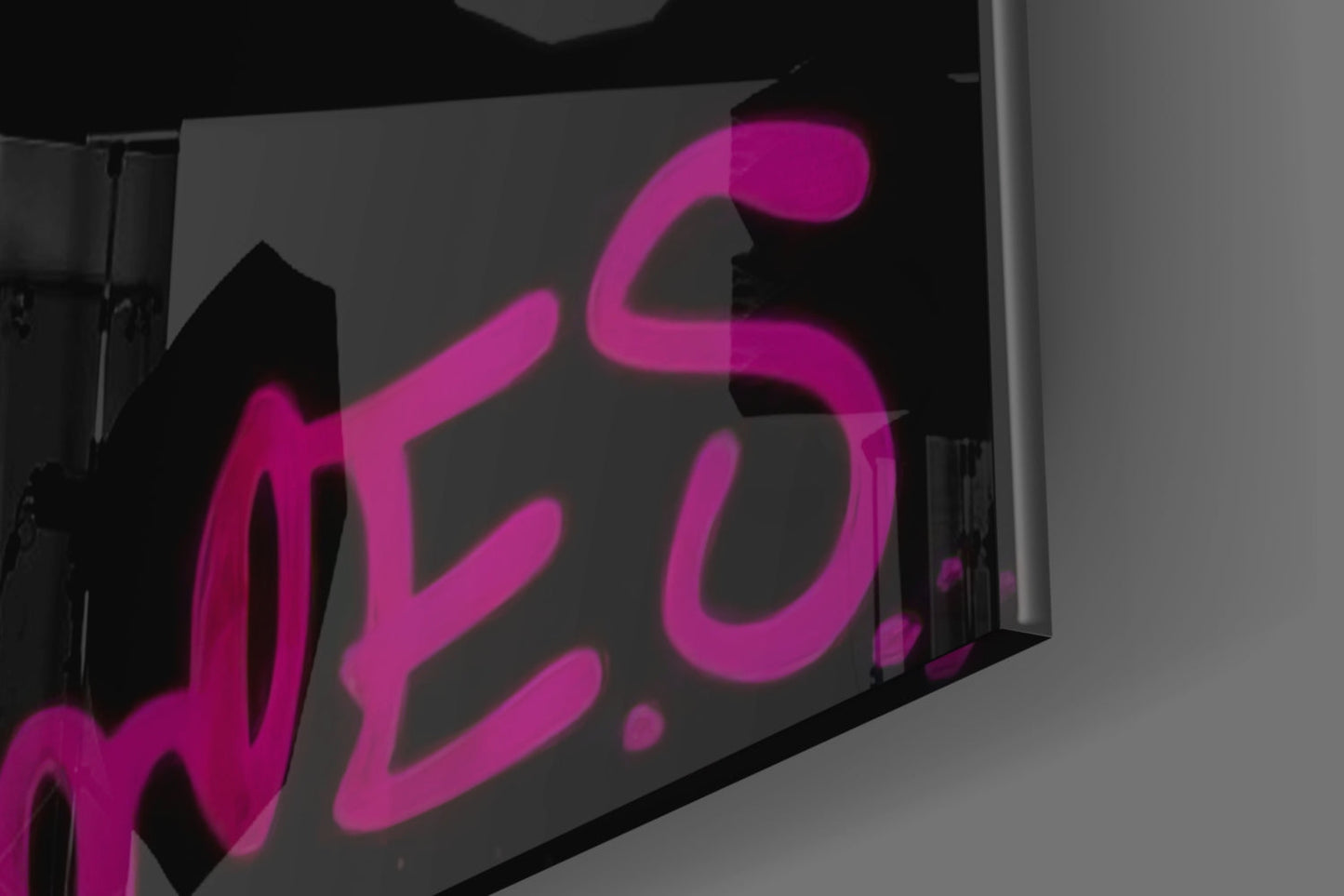 Pink neon-style Monkey Kiss glass wall art displayed at an angle against a gray background, showing the illuminated design detail.