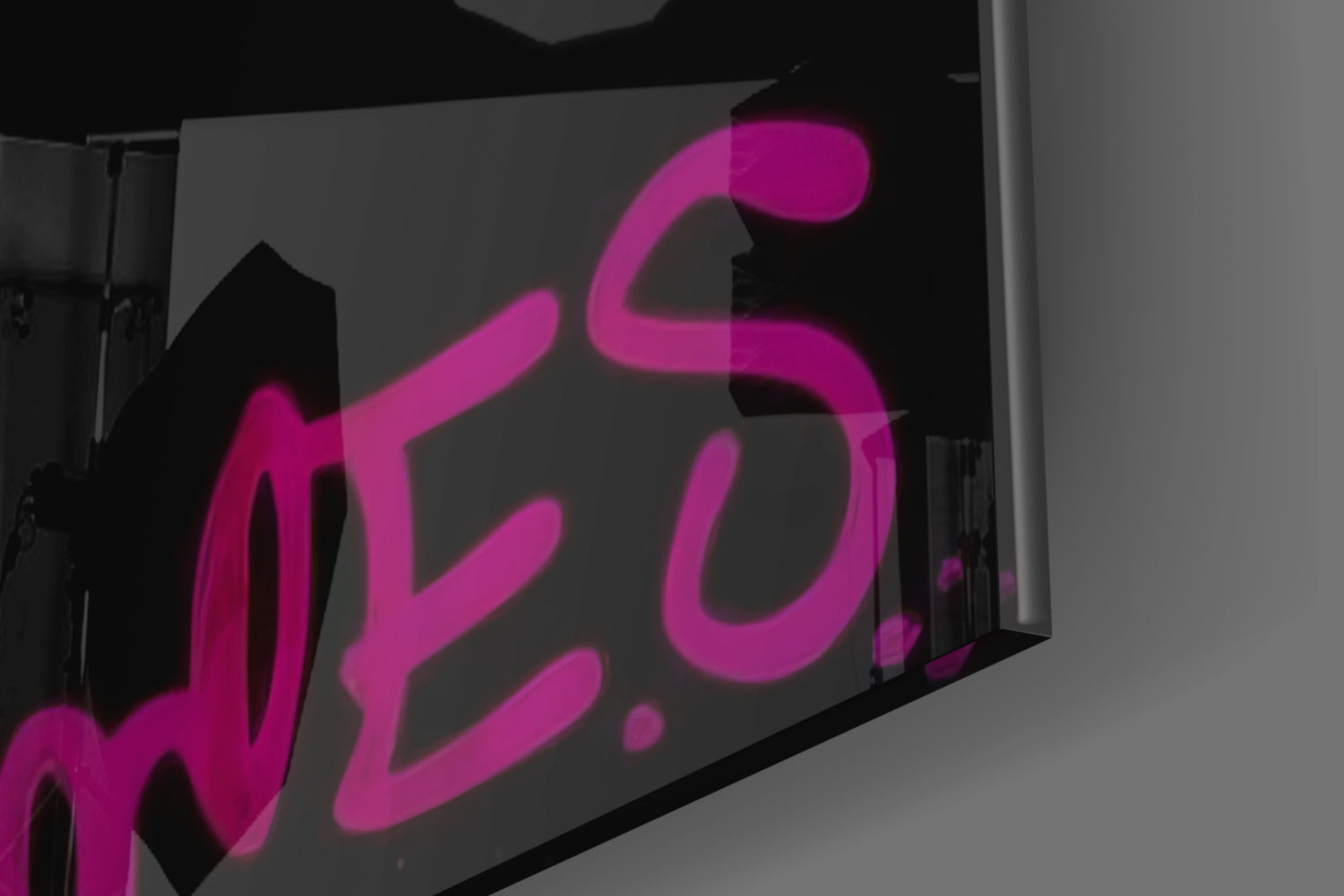 Pink neon-style Monkey Kiss glass wall art displayed at an angle against a gray background, showing the illuminated design detail.