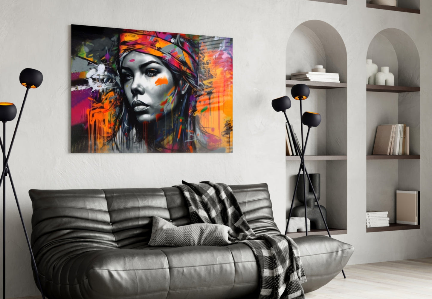 Colorful abstract portrait with vibrant orange, pink, and purple paint splashes on black and white face, displayed above gray leather sofa in modern living room.