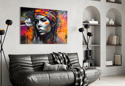 Colorful abstract portrait with vibrant orange, pink, and purple paint splashes on black and white face, displayed above gray leather sofa in modern living room.