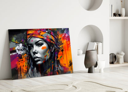 Colorful street art glass panel featuring a grayscale female face with vibrant orange, pink, and purple paint splashes, leaning against a white wall in a minimalist room setting.