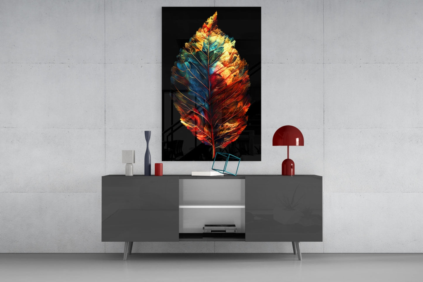 Colorful glass leaf artwork with red, orange, yellow, and blue tones displayed above a gray console table in a modern interior setting.