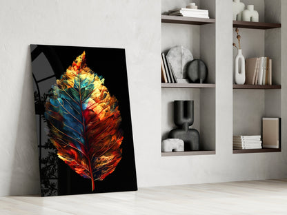 Colorful glass wall art featuring a glowing autumn leaf in red, orange, and blue tones leaning against a white wall beside open shelving.