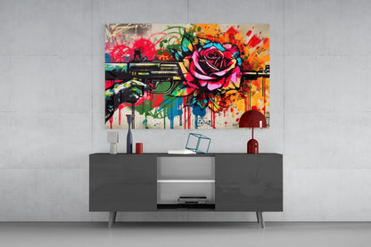 Vibrant pop art glass wall art depicting colorful flowers and a gun mounted above a dark gray media console in a modern interior setting.