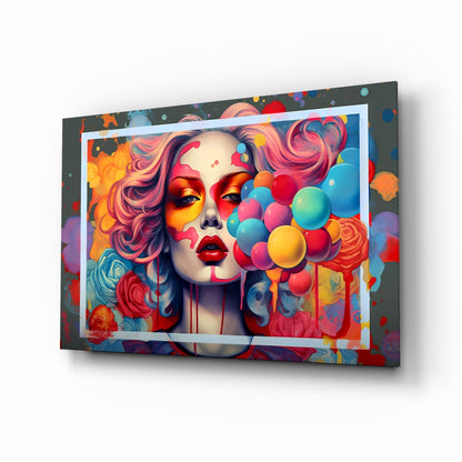 Angled perspective of colorful glass wall art featuring a woman's face with pink hair, red lips, and vibrant balloon designs in rainbow colors on dark background with white border.
