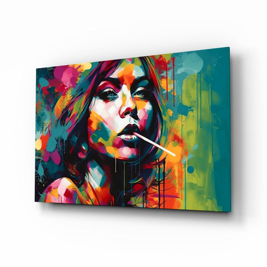 Angled view of a glass wall art panel featuring a colorful portrait of a woman with a cigarette, vibrant multicolored paint splashes in teal, pink, orange, and yellow tones against dark features.