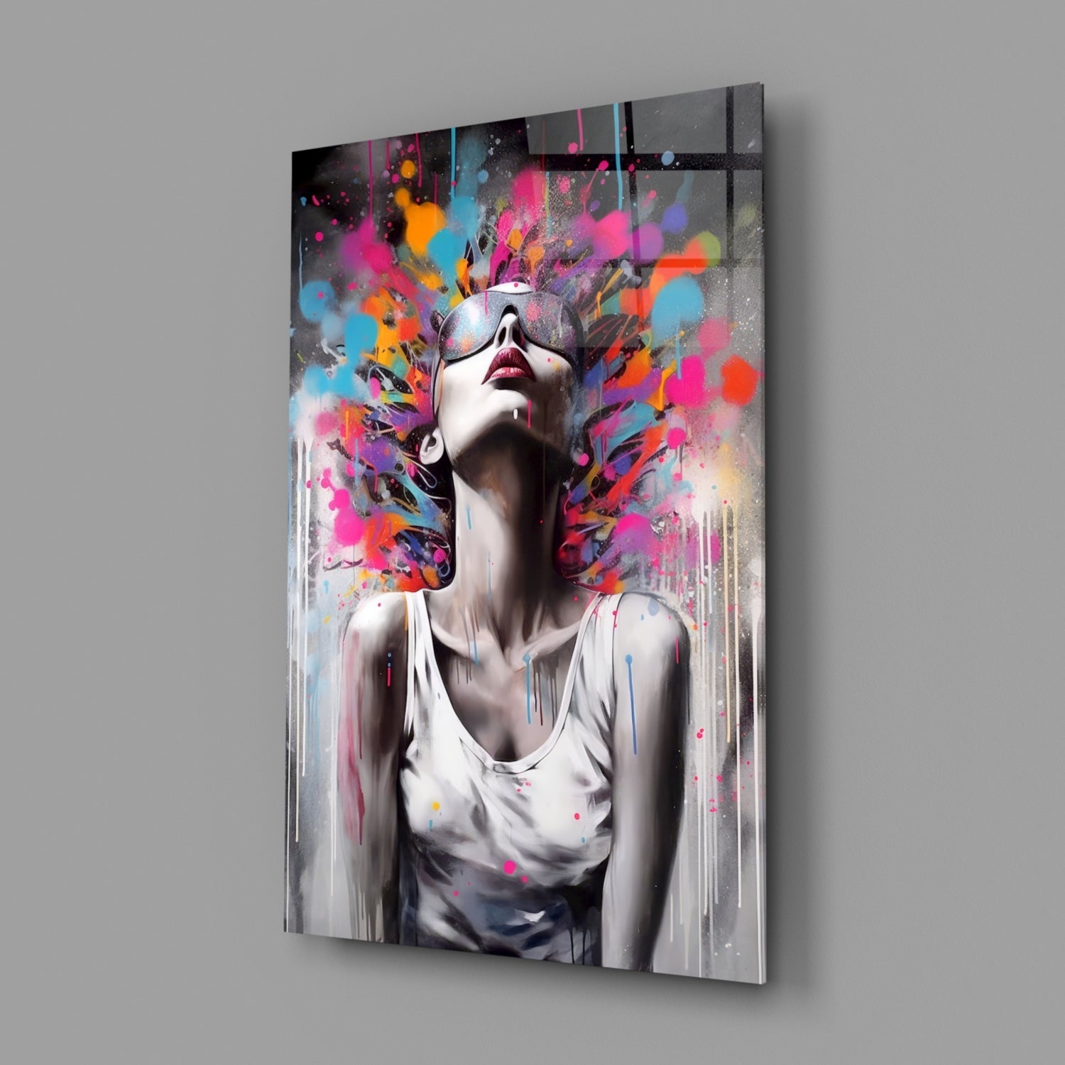 Modern glass wall art panel displaying a portrait of a woman wearing sunglasses with vibrant multicolored paint splatters exploding around her head against a white background.