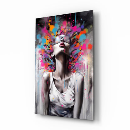 Glass wall art panel displayed at an angle showing a figure in sunglasses with colorful paint splatters exploding from head against white shirt.