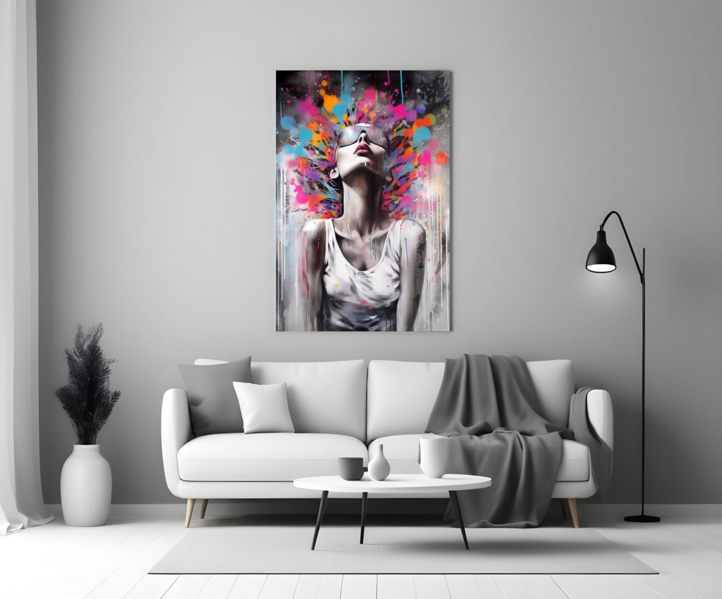 Colorful glass wall art depicting a woman with sunglasses and vibrant paint splashes above her head, displayed above a white sofa in a minimalist living room.