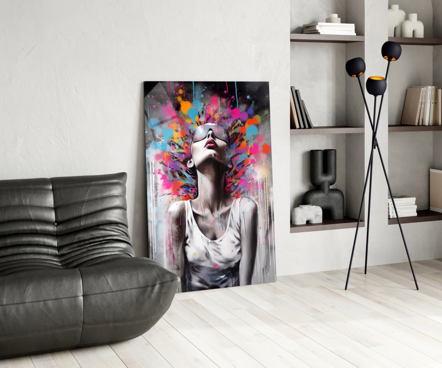 Modern living room interior with colorful abstract portrait glass art leaning against wall beside black leather sofa.