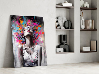 Colorful glass wall art leaning against white wall beside built-in shelving with decorative objects and books.