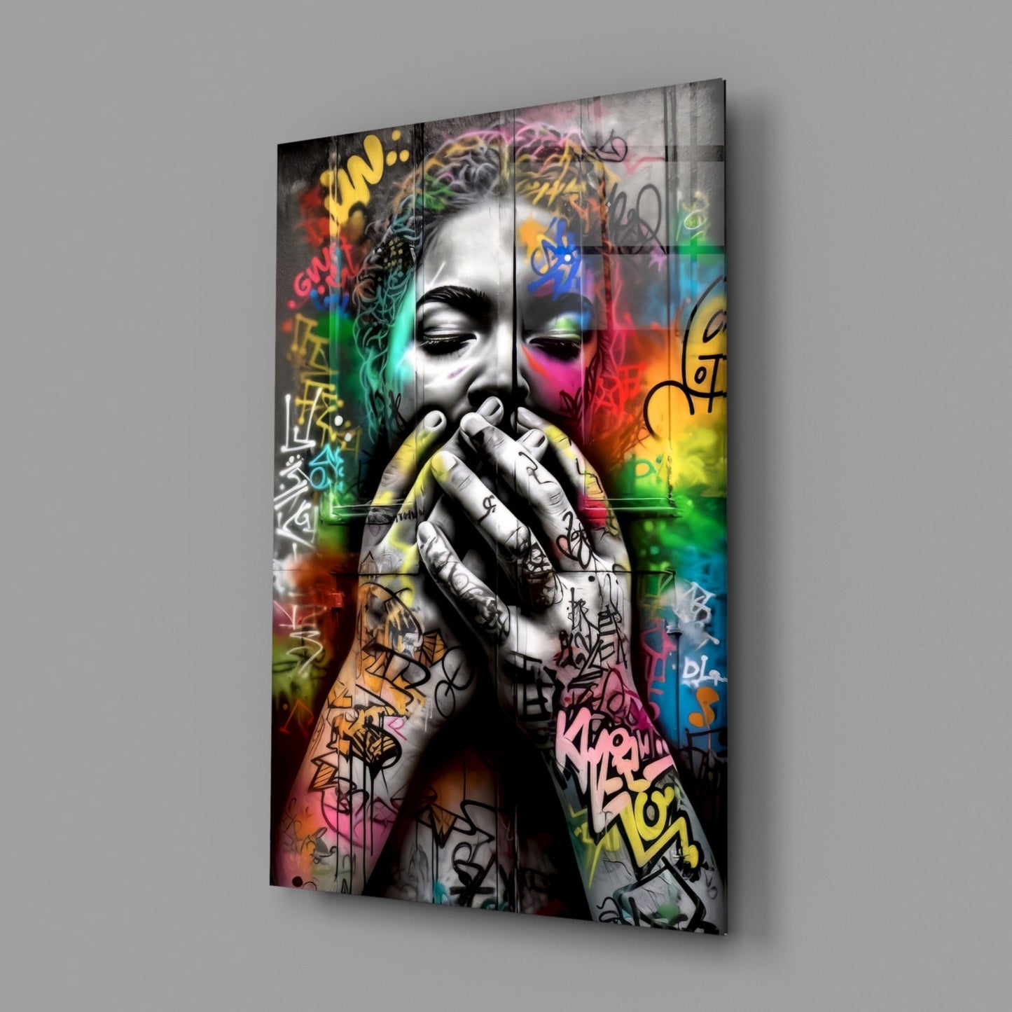Angled view of glass wall art depicting a monochromatic face with colorful graffiti tags and vibrant rainbow gradients across the surface.