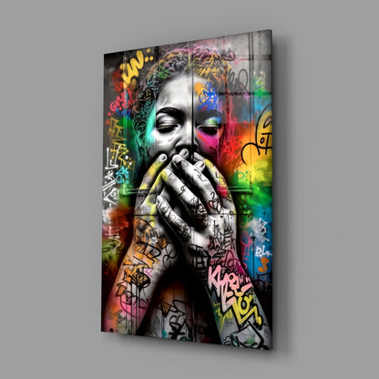 Angled view of glass wall art depicting a monochromatic face with colorful graffiti tags and vibrant rainbow gradients across the surface.