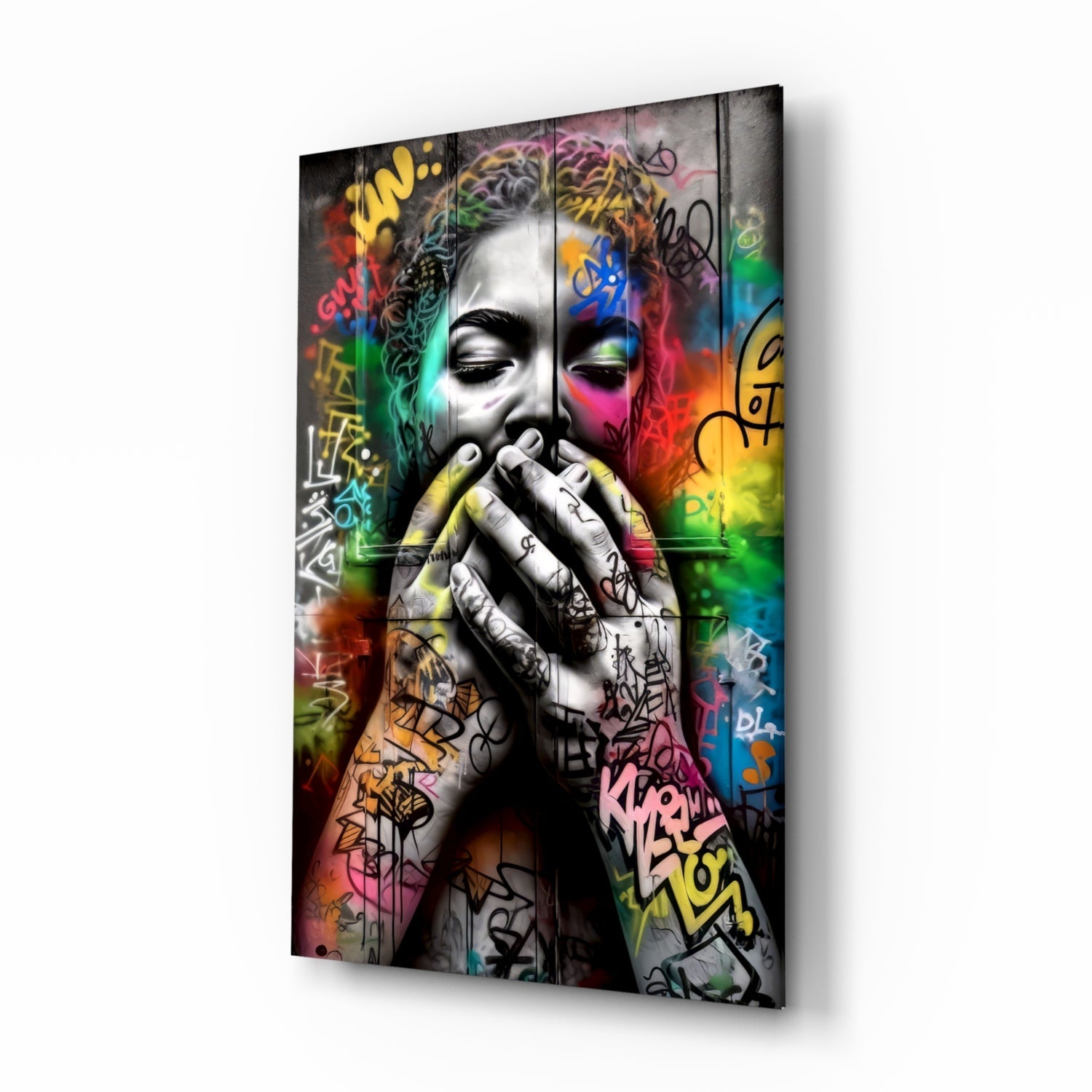 Angled three-quarter view of glass wall art featuring monochrome face with colorful graffiti, rainbow gradient background, and tattooed hands.