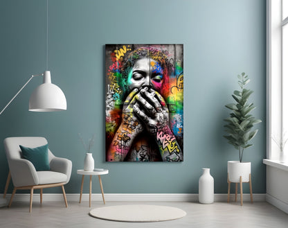Colorful street art glass panel depicting a portrait with graffiti and rainbow paint effects, displayed on a teal wall in a modern living room setting.
