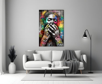 Colorful graffiti-style glass wall art depicting a contemplative face with vibrant multicolored street art background, displayed above a white sofa in a modern living room.