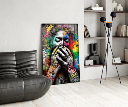 Colorful street art portrait on glass panel displayed in modern living room with grey sofa and shelving.