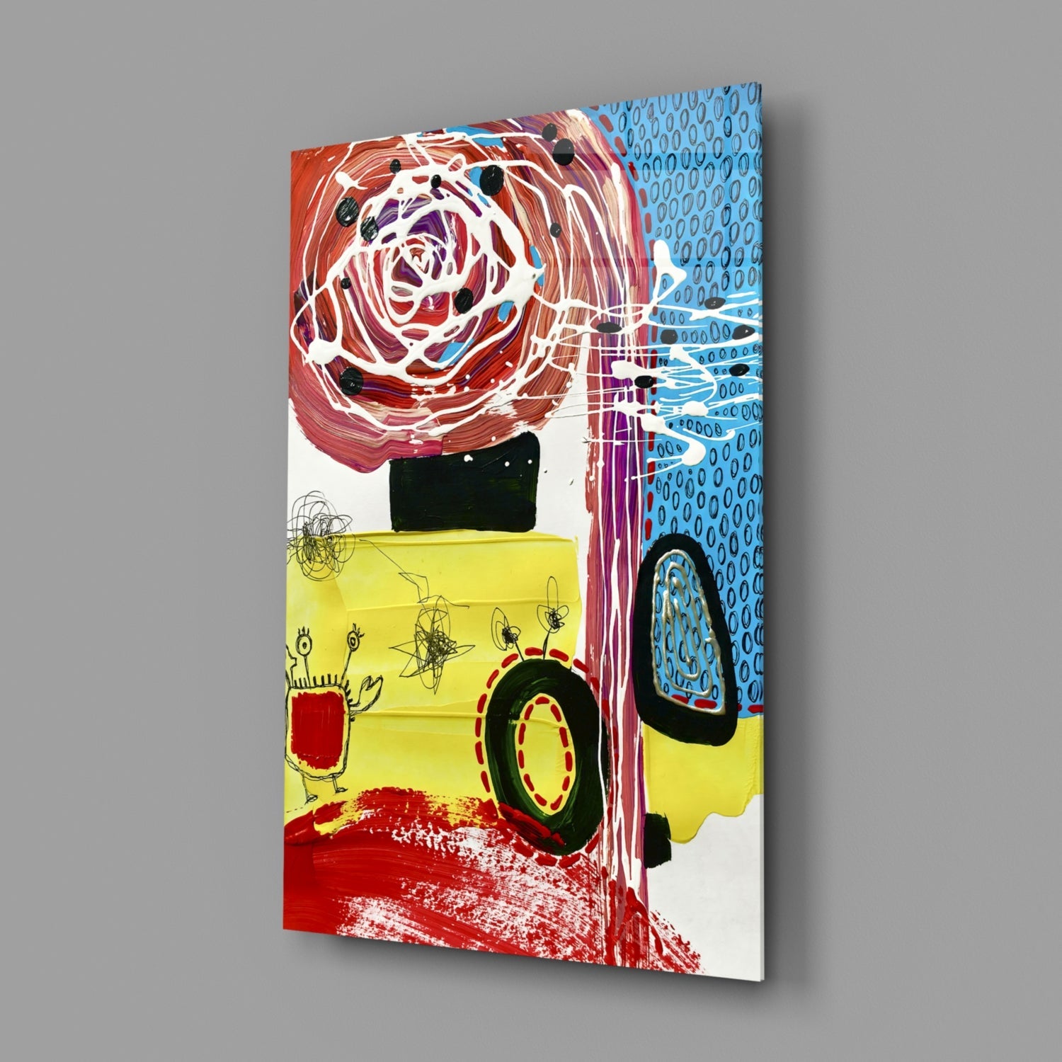Angled view of a glass wall art panel featuring a vibrant mixed-media collage with a red rose, yellow vehicle, blue patterned background, and black silhouettes.