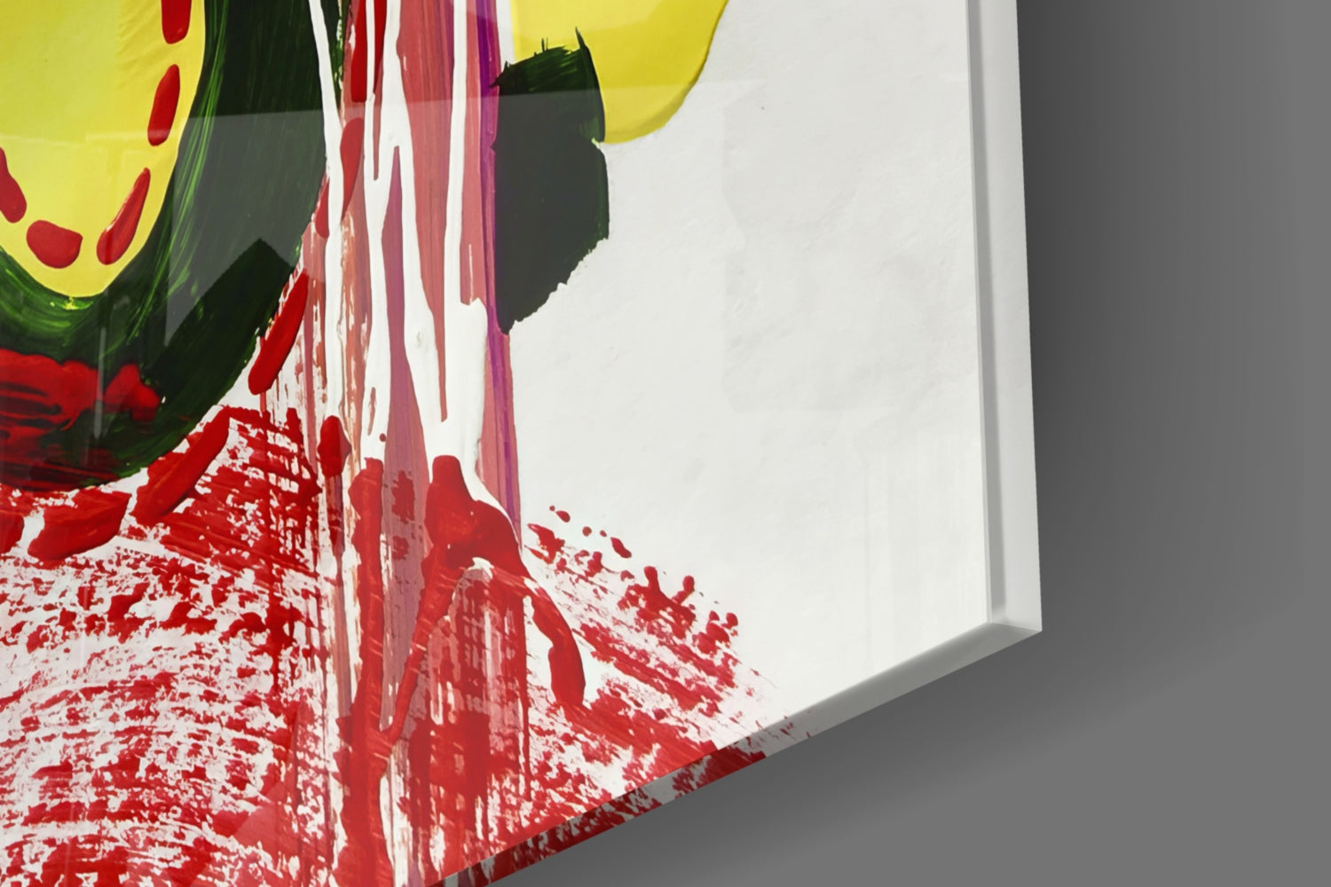 Angled close-up view of colorful glass wall art with red splatter pattern, yellow circle, green and black brushstrokes on white background.