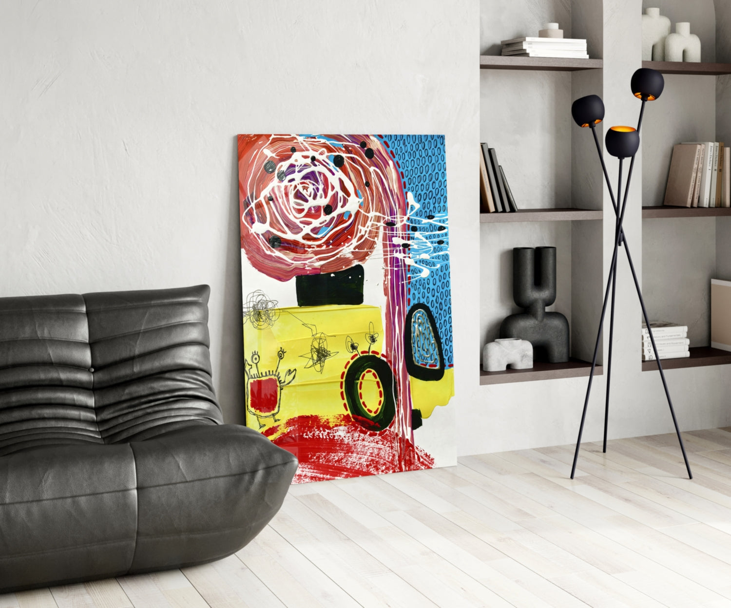Colorful glass wall art featuring an abstract yellow vehicle with red circular elements and blue patterned background, displayed in modern living room with gray sofa and shelving.