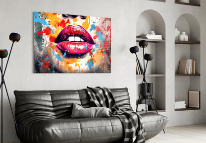 Colorful pop art glass wall panel featuring vibrant red lips with splattered blue, yellow, and orange paint displayed above a gray leather sofa in a modern living room.