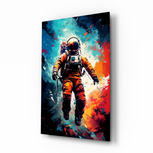 Angled view of glass wall art featuring an astronaut in orange suit floating against blue and red painted background with paint splatter effects.