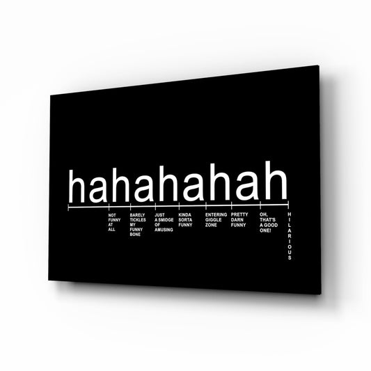 Black glass wall art panel displayed at an angle, showing white "hahahaha" text with a laughter intensity scale beneath it.