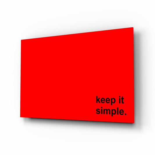 Red glass wall art with black text reading "keep it simple." displayed at an angled perspective against white background.