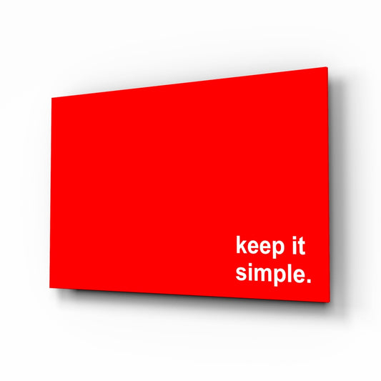 Red glass wall art panel with white text "keep it simple." displayed at an angled perspective.