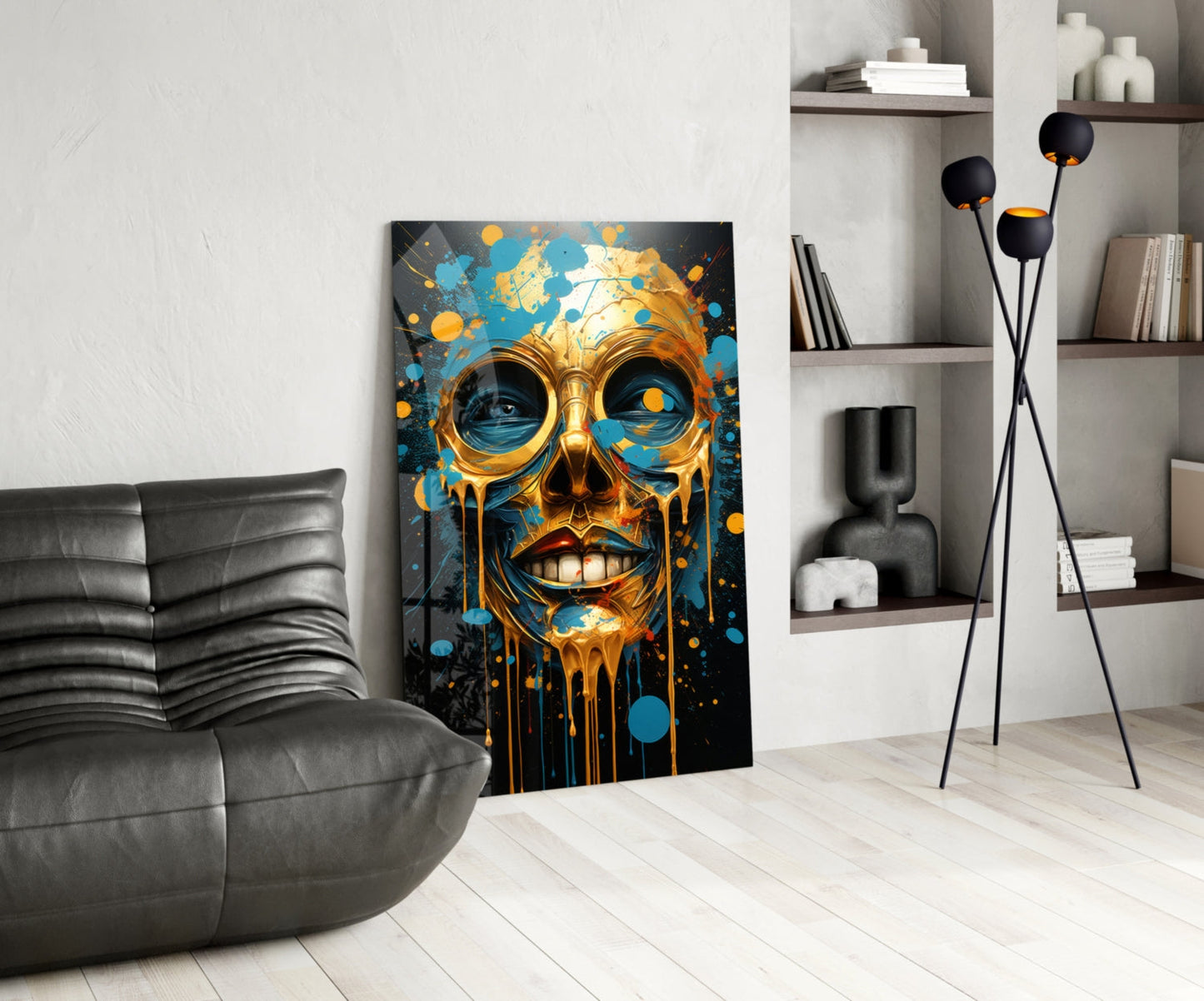 Modern living room featuring gold and blue abstract skull artwork leaning against wall beside gray leather chair.