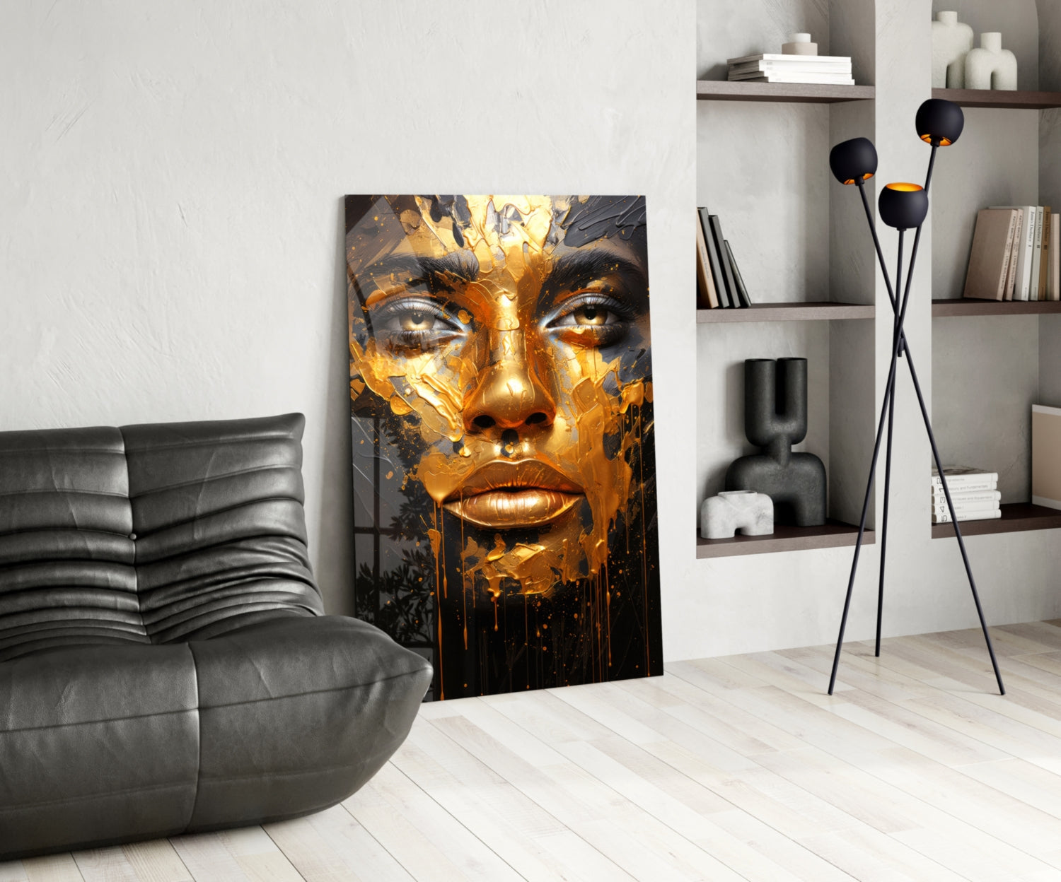 Modern living room interior with golden and black face portrait glass art leaning against white wall beside gray leather chair.