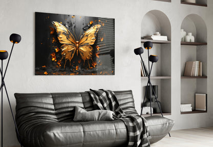 Golden butterfly glass wall art with orange and black splatter effect displayed above gray leather sofa in modern living room.