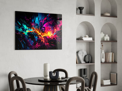 Vibrant abstract glass wall art with cyan, magenta, yellow and orange explosive splashes displayed above a black dining table in a modern interior.