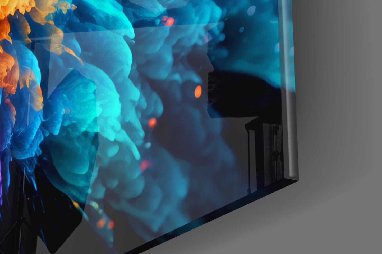 Angled view of glass wall art displaying vibrant blue and orange abstract flowers against gray background.