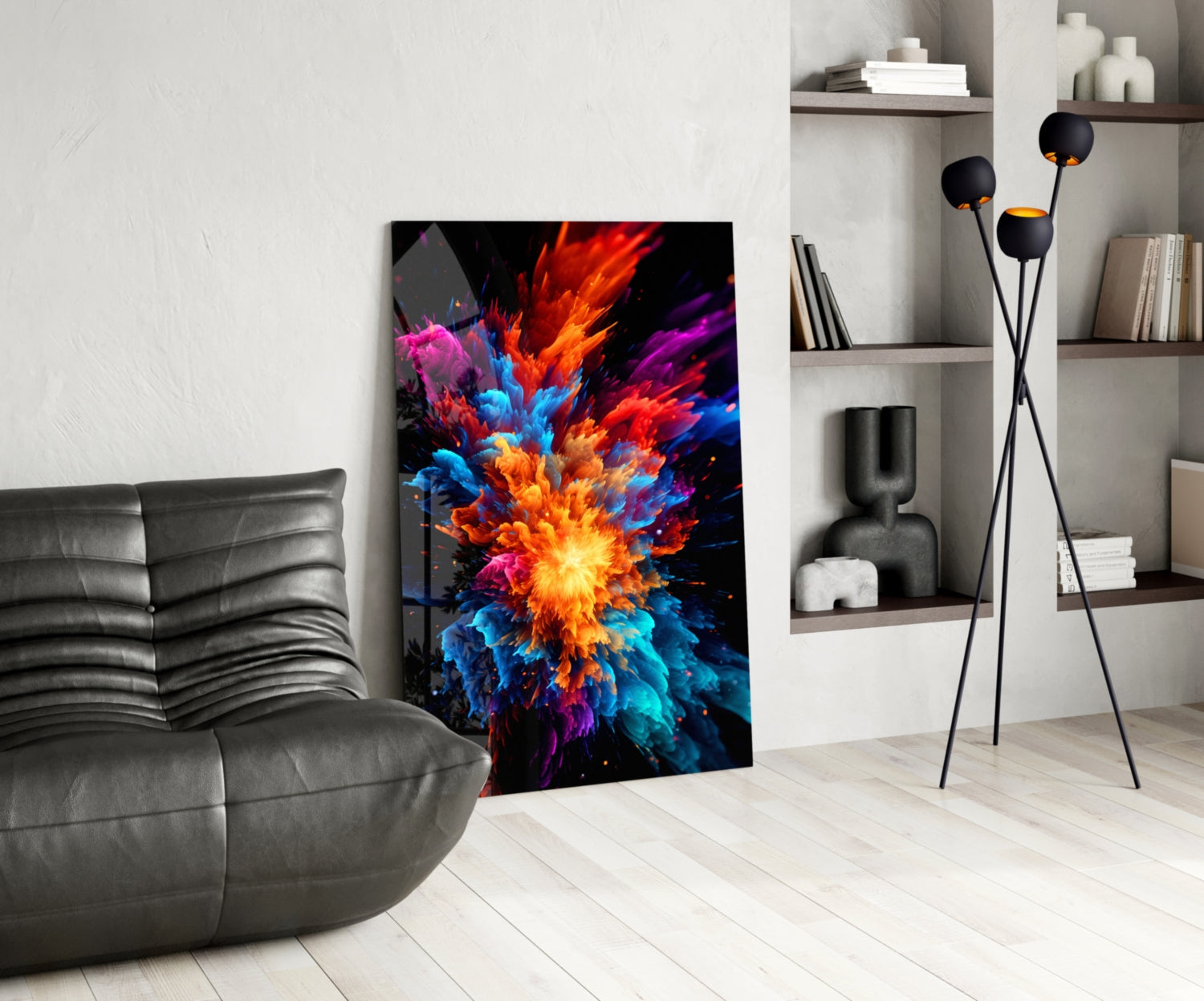 Vibrant multicolored abstract explosion artwork displayed on black glass panel in modern living room with gray sofa and shelving.