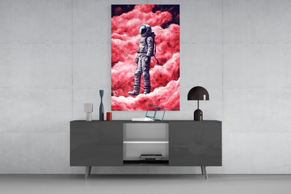 Modern living room display featuring framed glass wall art of an astronaut standing amid pink clouds, mounted above a dark console table with decorative accessories.