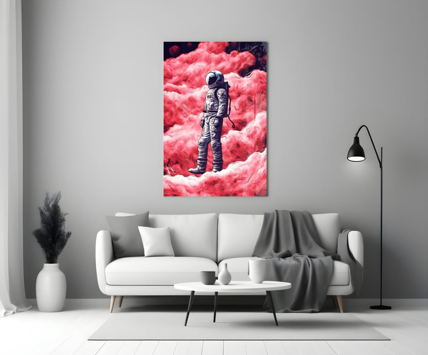 Glass wall art depicting an astronaut in spacesuit standing on a vibrant pink cloudy landscape, displayed above a white sofa in a modern living room.