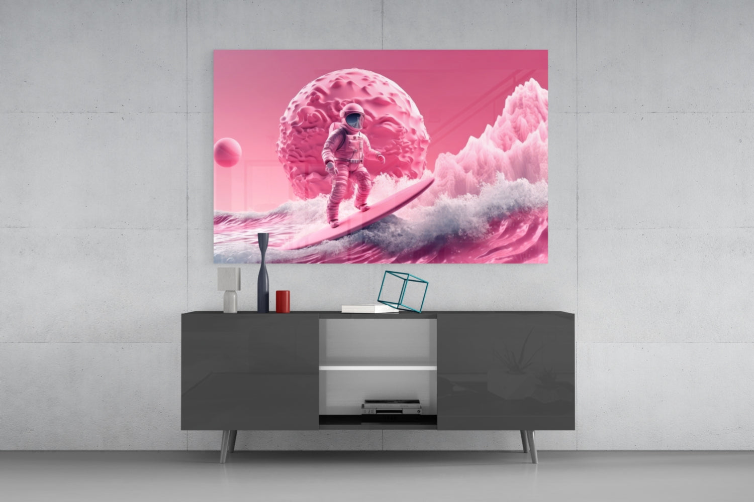 Pink glass wall art depicting an astronaut surfing on waves beneath a textured pink planet, displayed above a dark modern media console.