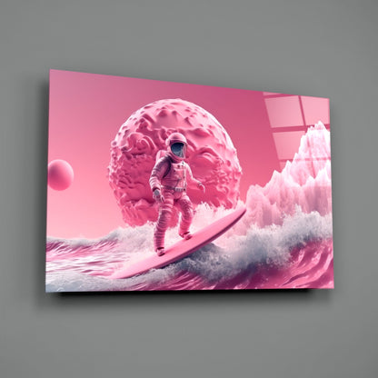Pink glass wall art panel displaying an astronaut surfing on waves beneath a giant brain-shaped planet against a monochromatic pink sky.