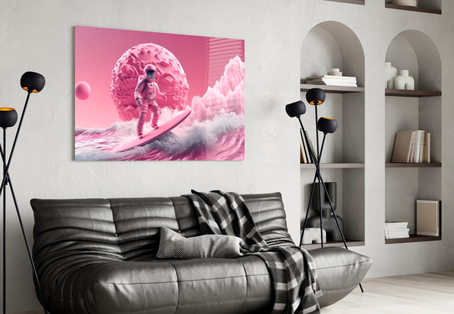 Pink and white glass wall art depicting an astronaut on a surreal landscape, displayed above a black leather sofa in a modern interior setting.