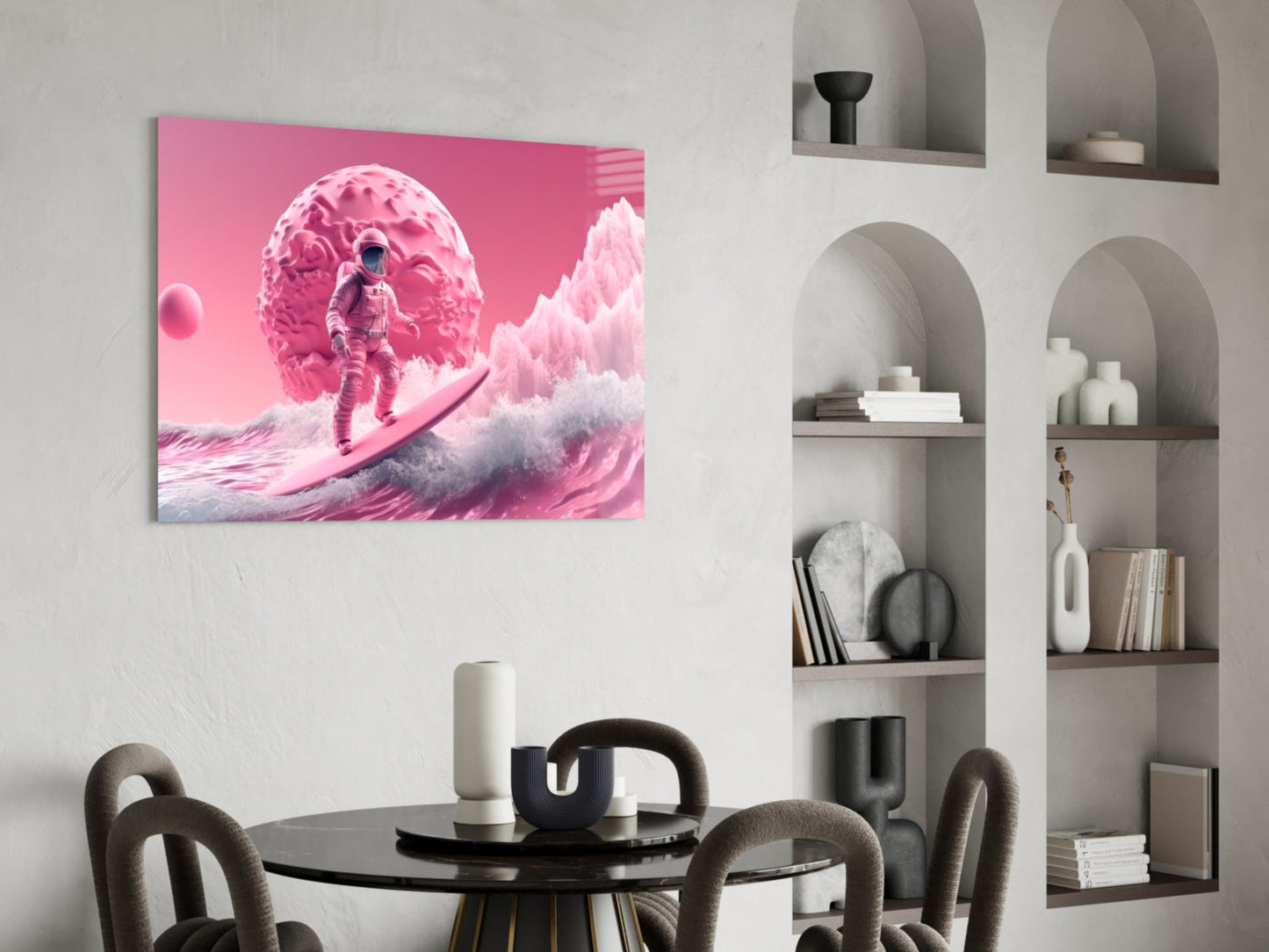 Pink glass wall art depicting an astronaut surfing giant waves beneath a massive pink planet, displayed above a black round dining table.