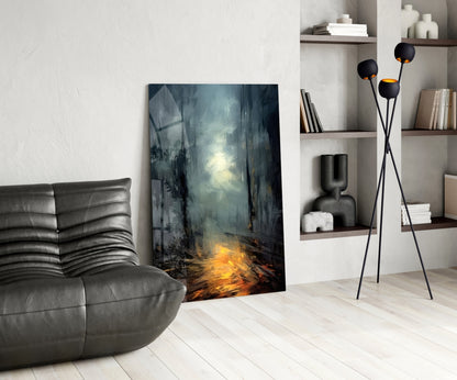 Dark moody forest scene glass wall art leaning against white wall beside gray leather chair.