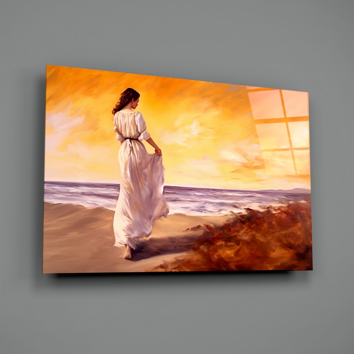 Woman in white dress standing on beach at sunset, displayed as glass wall art mounted on gray wall.