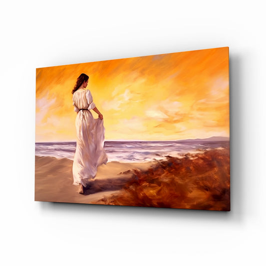 Woman in white flowing dress standing on sandy beach at sunset, displayed as angled glass wall art panel.