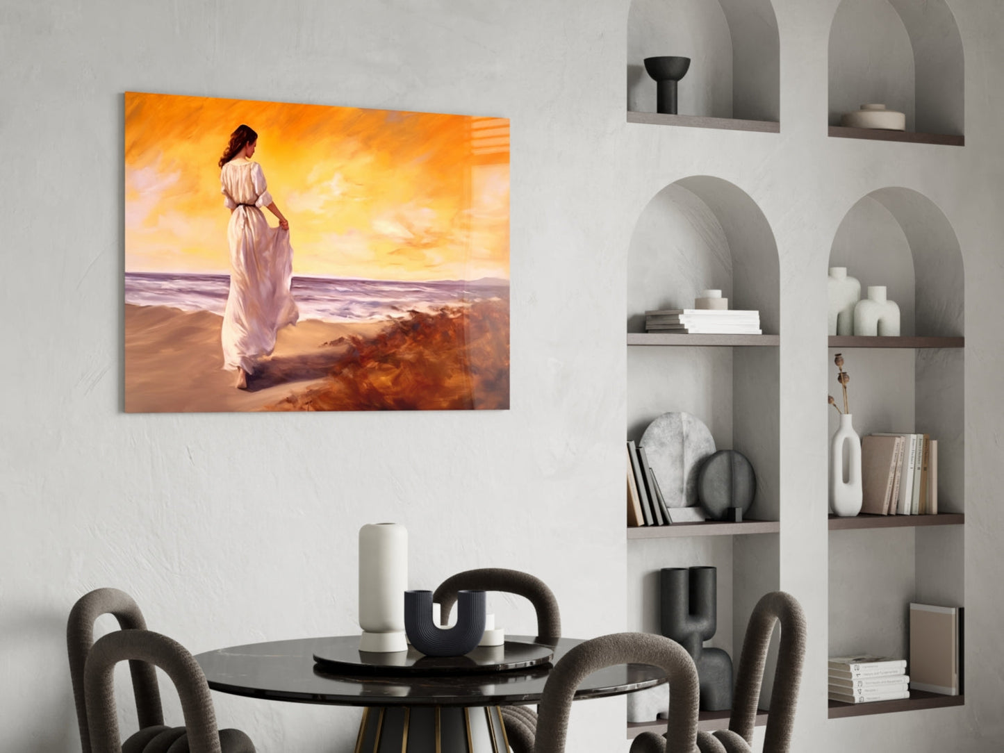 Glass wall art displaying woman in pink dress standing on beach at sunset, hung above round dining table in modern interior.