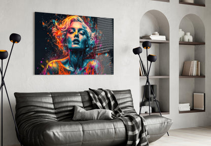Colorful abstract portrait glass wall art with neon orange, pink, and blue tones displayed above a gray leather sofa in modern living room.